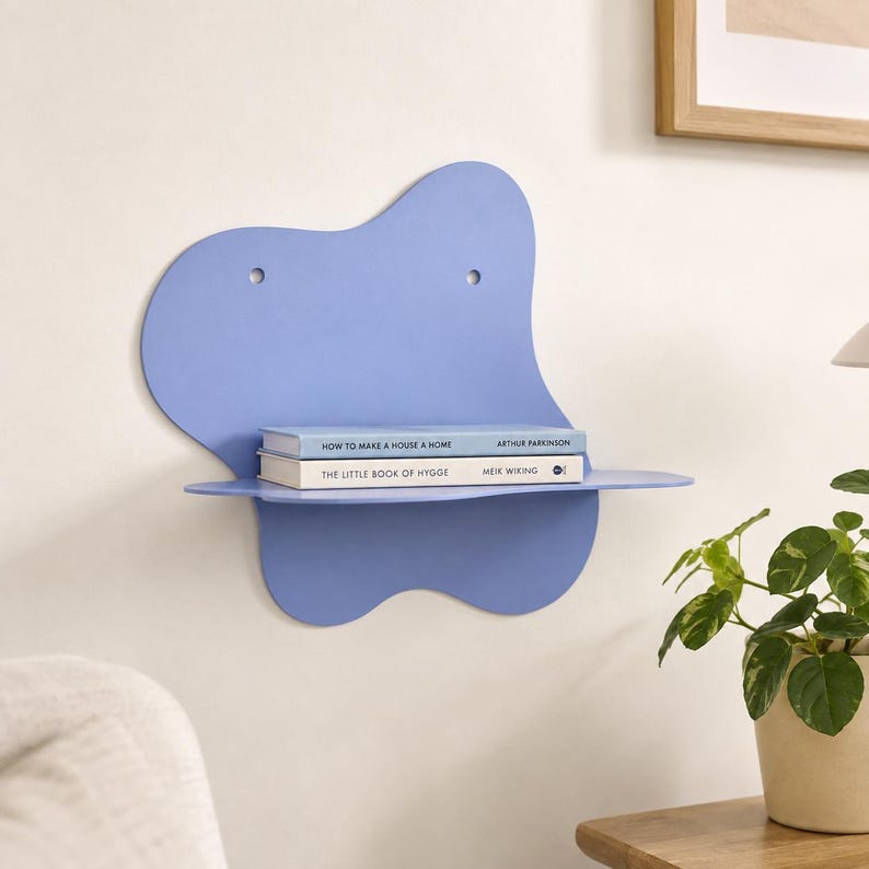 Abstract metal floating wall shelf with wavy back panel displaying a small vase and decorative dish