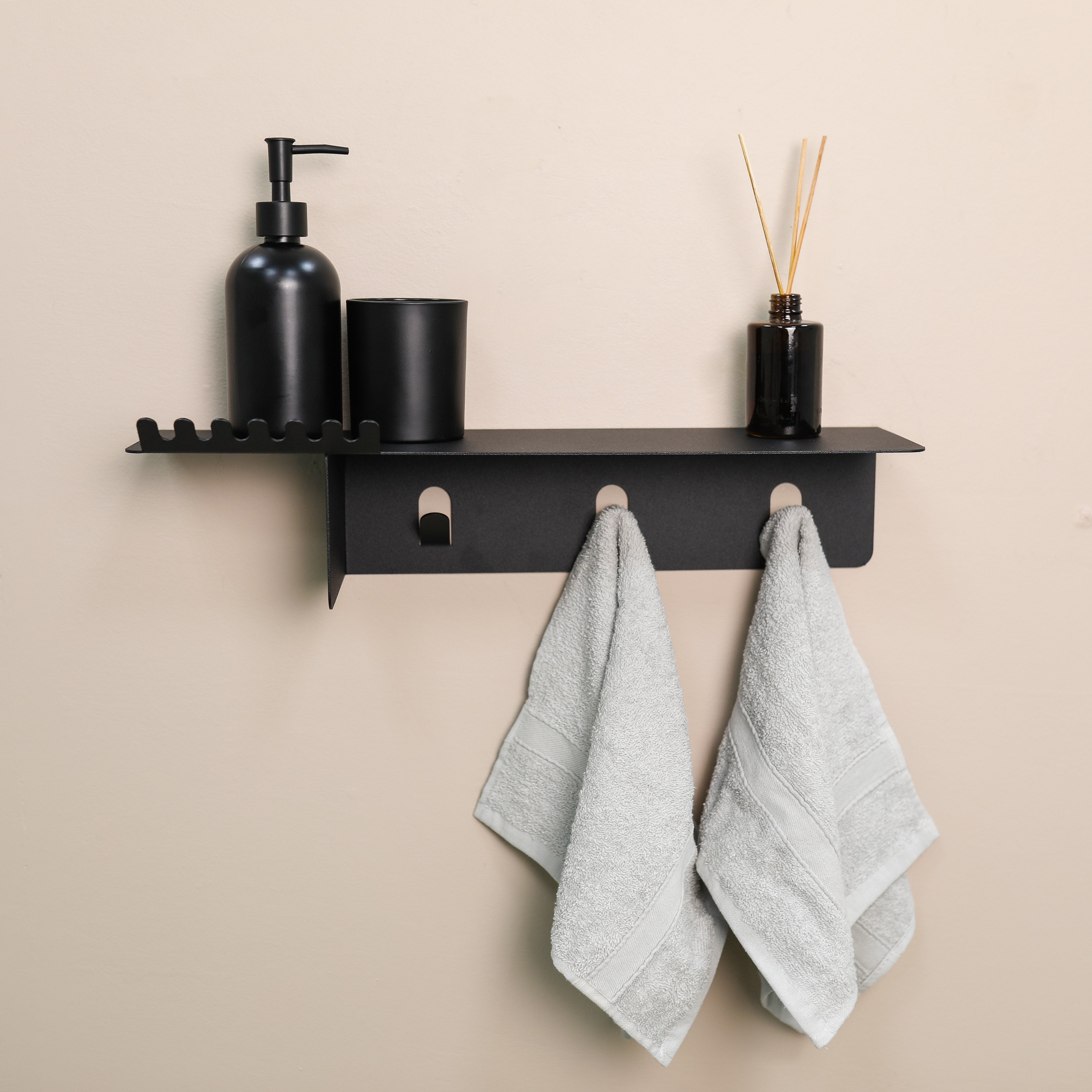 Black wall shelf with towels and bathroom items on a beige wall