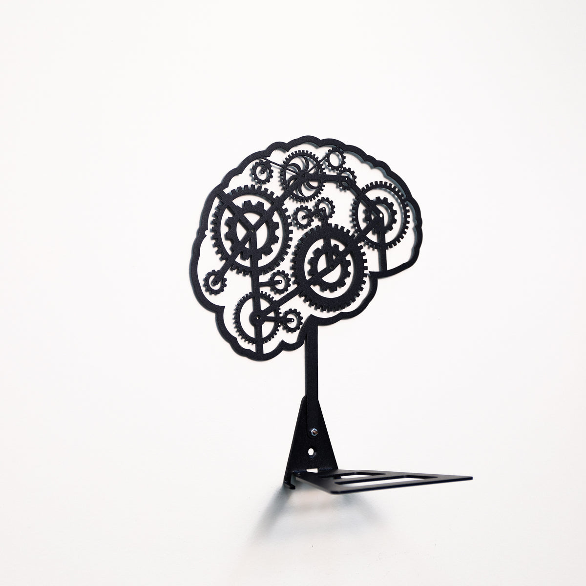 A black metal decorative sculpture shaped like a stylized brain made of interlocking gears, mounted on a small stand against a plain white background.