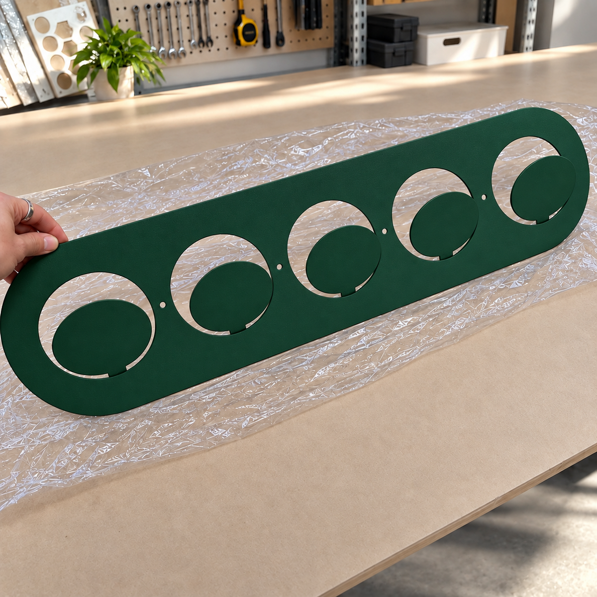 Dark green metal wall hook rack with circular hooks holding handbags in a modern entryway