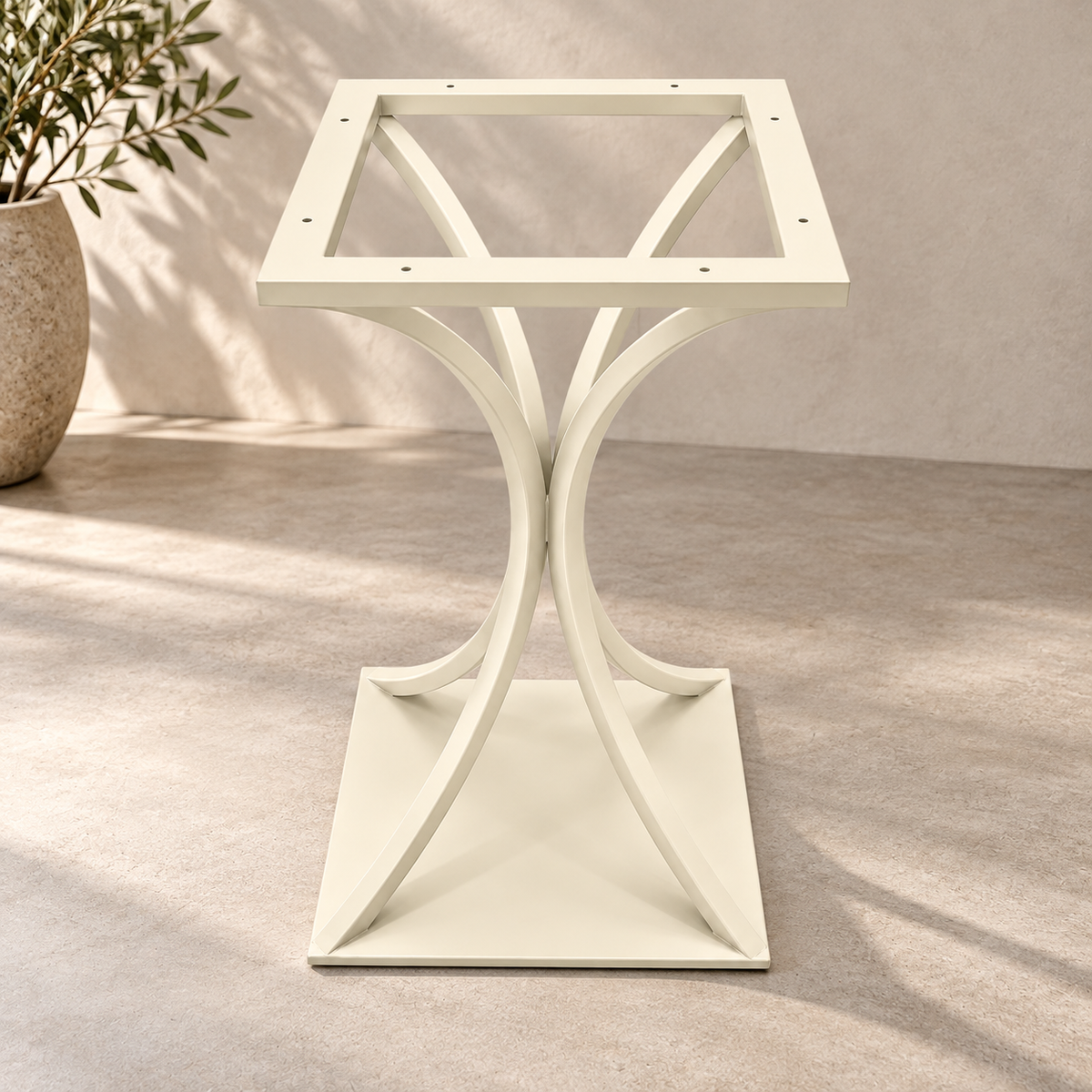 An off-white square table base frame with a sculptural, curved cross-legged pedestal design and a flat square base, shown in a styled interior setting with a potted plant in the background.