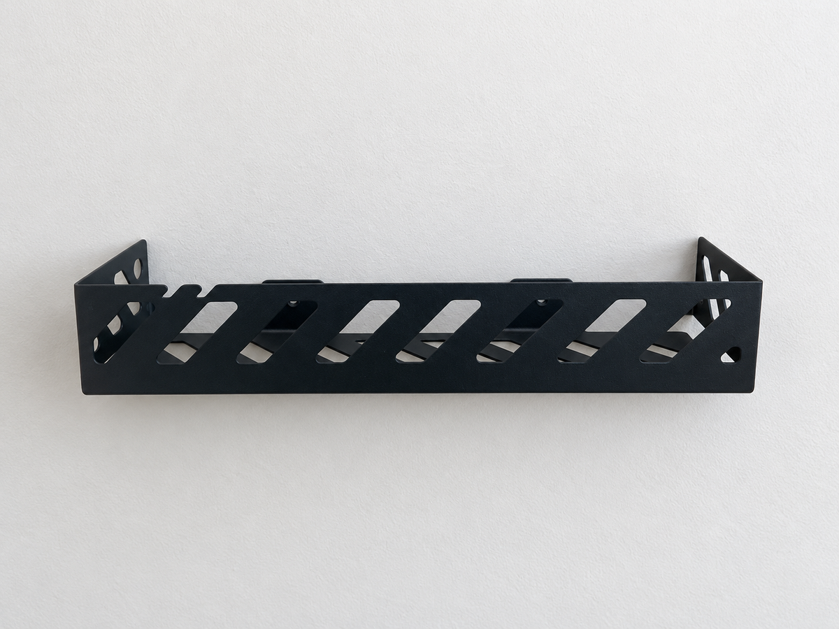 Black metal bathroom wall shelf with geometric cutouts holding toiletries, soap dispensers and toothbrushes