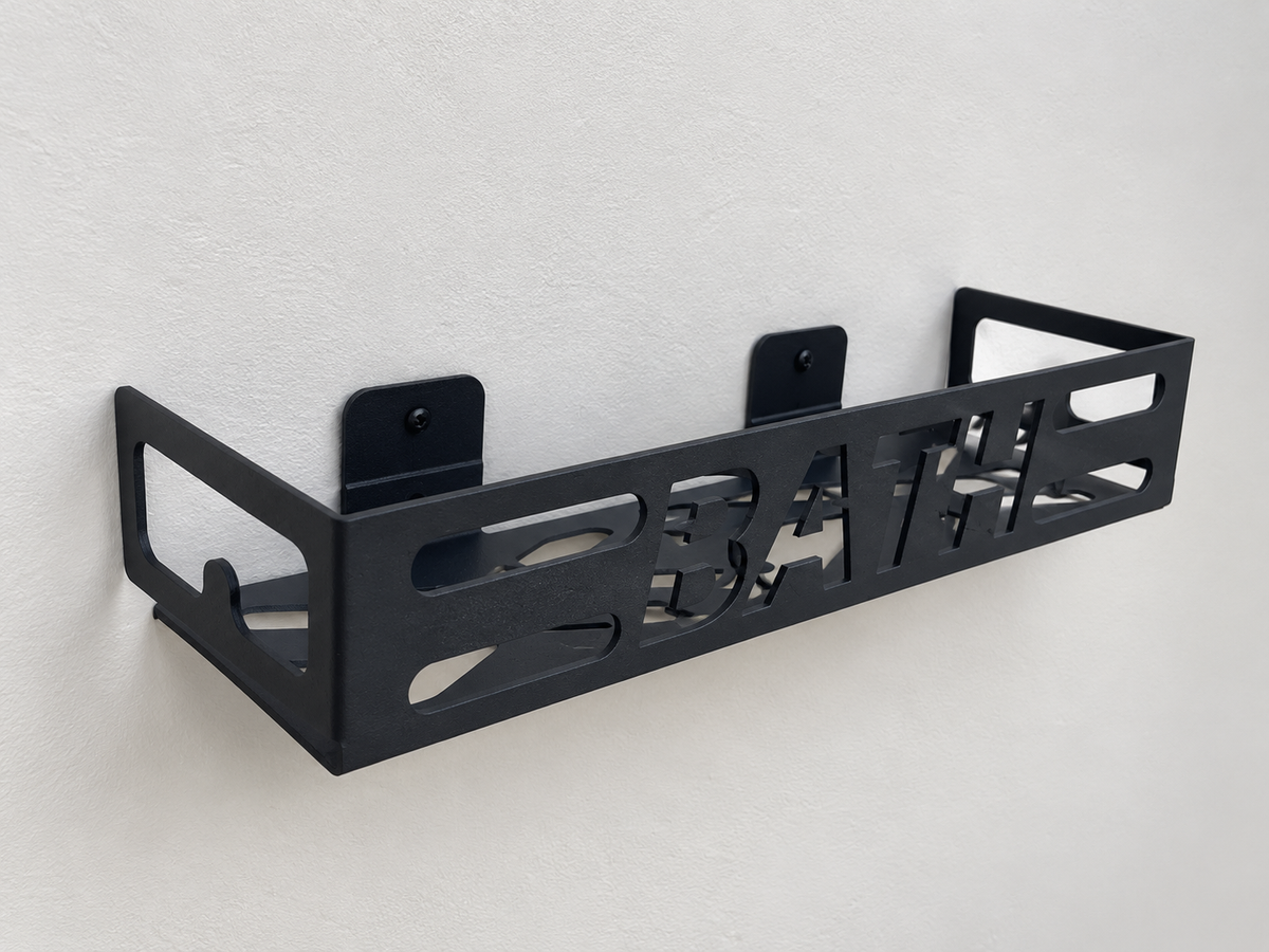 Black metal bathroom wall shelf with cutout BATH lettering, geometric openings and wall-mounted brackets