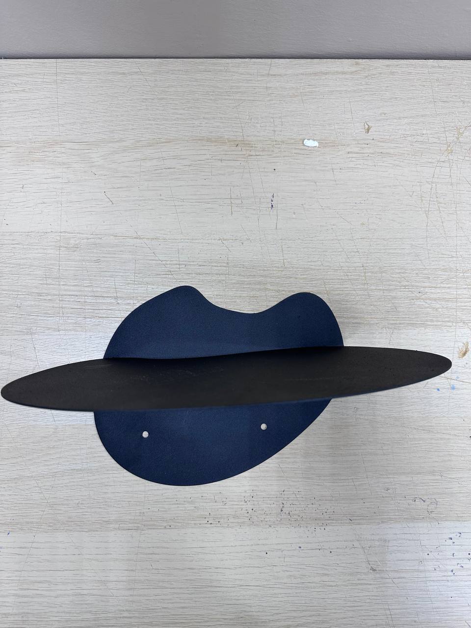  abstract metal floating wall shelf with curved back panel displaying a small succulent and notebook