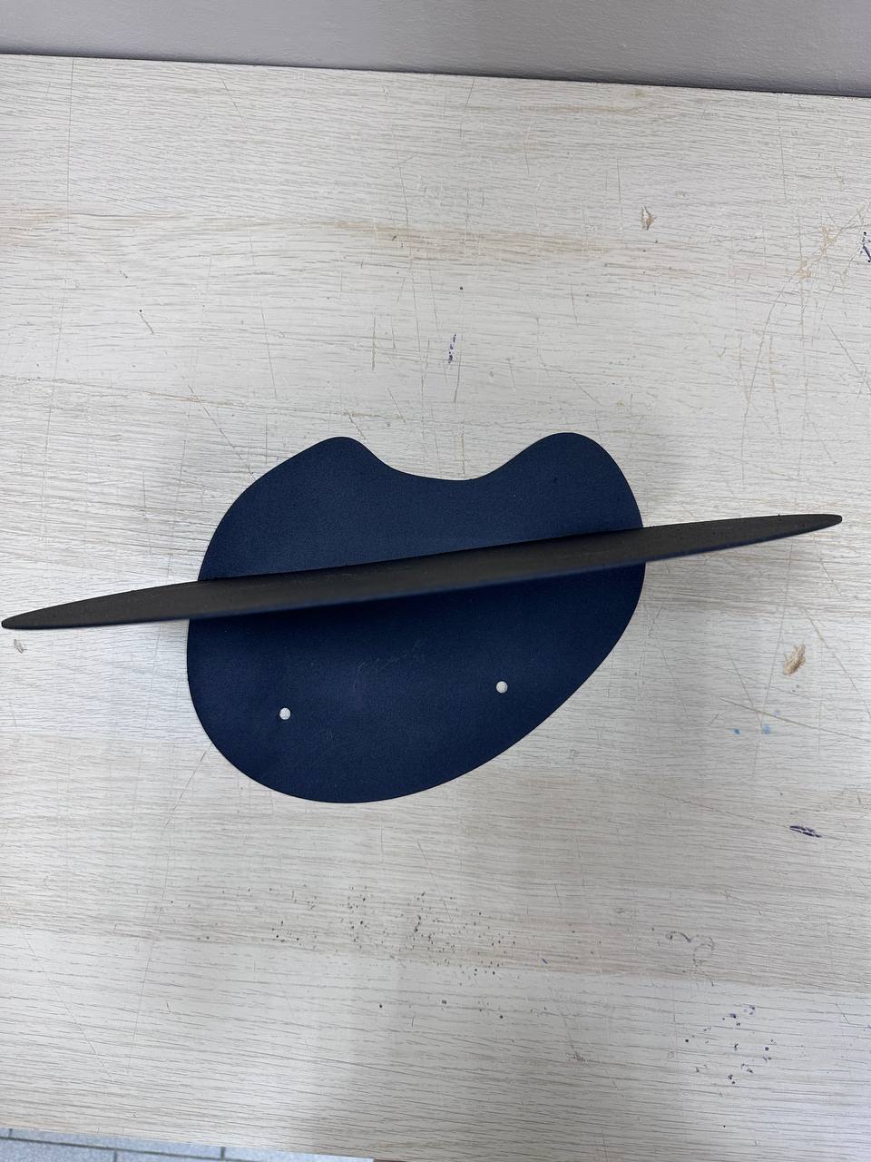  abstract metal floating wall shelf with curved back panel displaying a small succulent and notebook