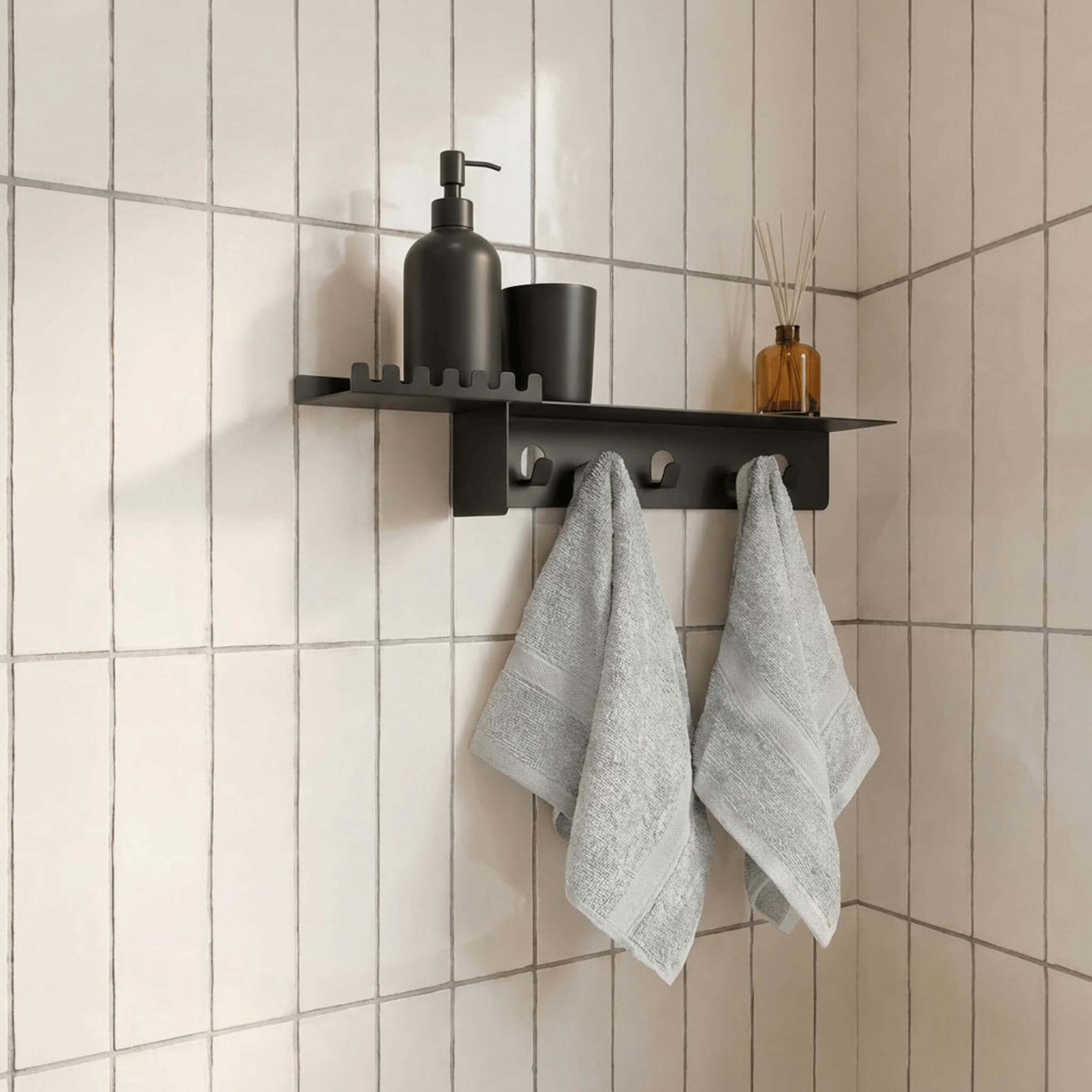 Black wall-mounted shelf with towels and bathroom items on a tiled wall.