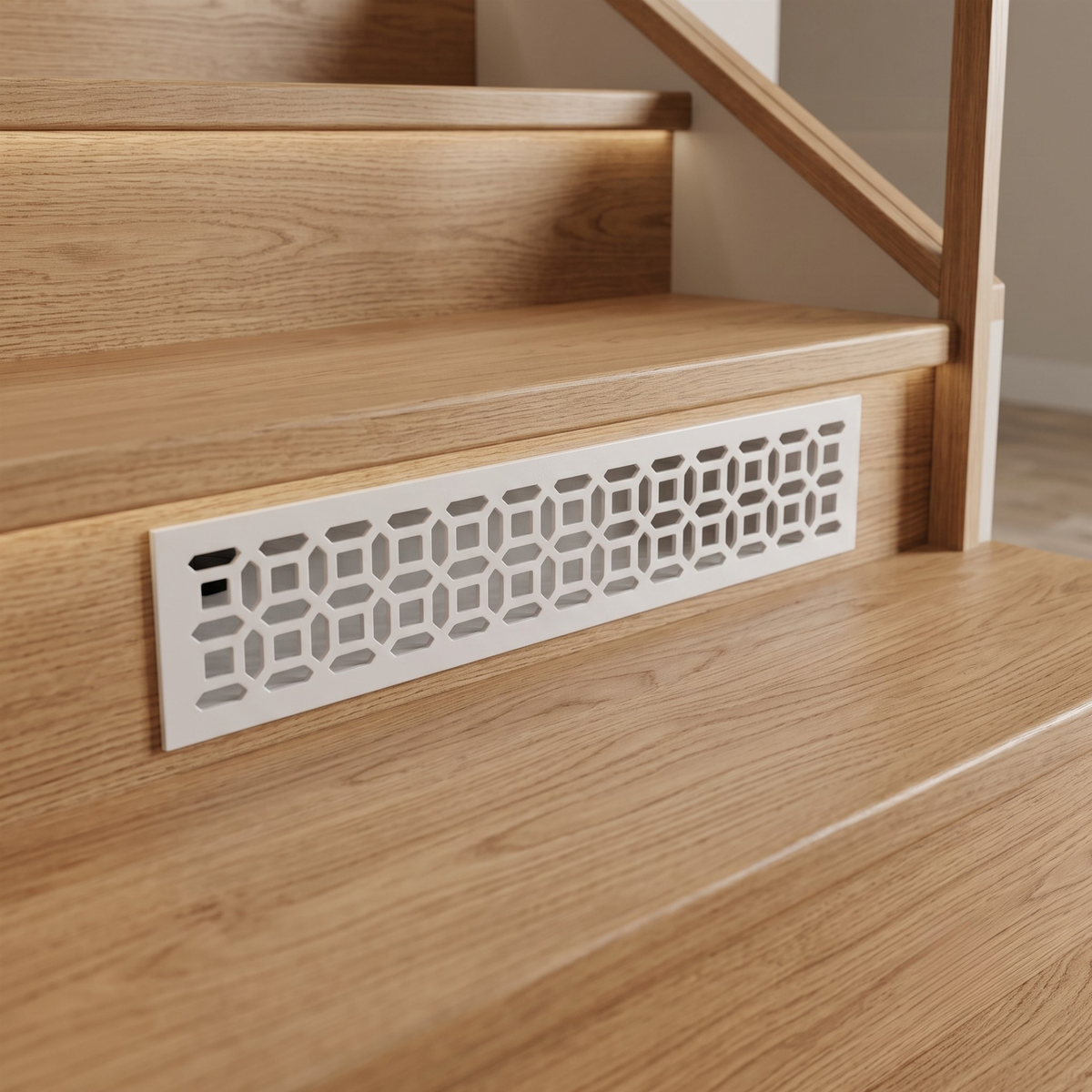 A white metal staircase riser with a geometric cutout pattern, installed on a wooden staircase step.
